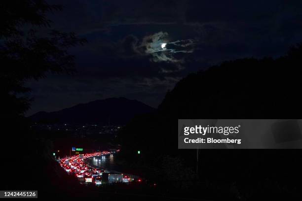 Vehicles queue in a traffic jam on the Chuo Expressway as August's full moon, also known as Sturgeon Moon, rises in Uenohara, Yamanashi Prefecture,...