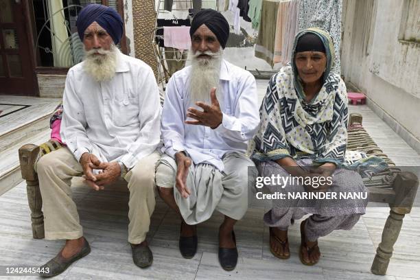 In this picture taken on August 3 Baldev Singh speaks during an interview with AFP as his wife Jasbir Kaur and brother Gurmukh Singh watch in...