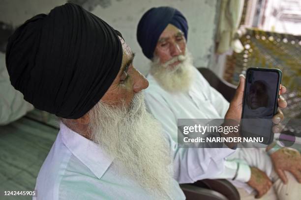 In this picture taken on August 3 Baldev Singh and his brother Gurmukh Singh display a picture of their sister Mumtaz Bibi on a mobile phone in...