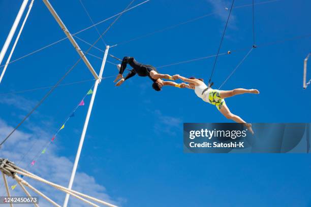 trapeze kunstenaars vangen en opknoping in de lucht - onderdeel van de serie - caught in the act stockfoto's en -beelden