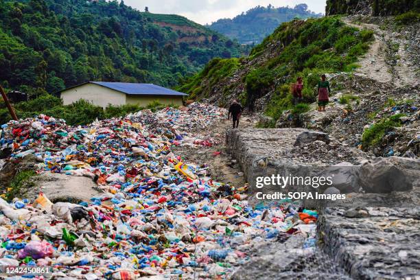 People walk along the highway filled with garbage near the waste dumping site in Kathmandu. The road section leading to the landfill site has ongoing...