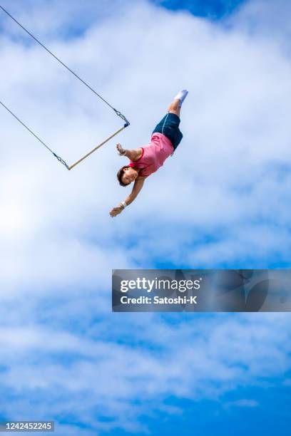 artista trapezio femminile che vola nel cielo blu - trapezista foto e immagini stock