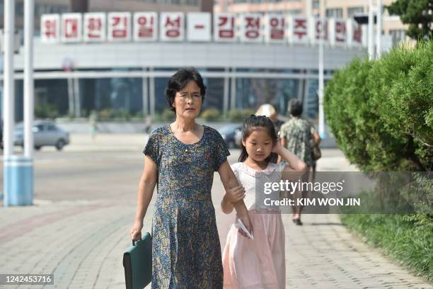 Woman and a young girl walk along Ryomyong street in Pyongyang on August 12, 2022.