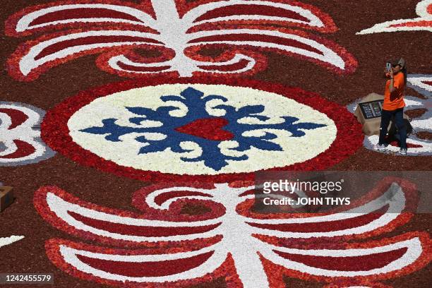 Volunteer takes a photo as she works on the creation of the Flower Carpet on the Grand-Place in Brussels on August 12, 2022. - The 22nd edition of...