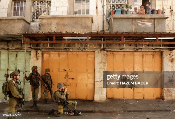 Children watch from a balcony as members of the Israeli security forces take position in front of a building, during confrontations with Palestinian...