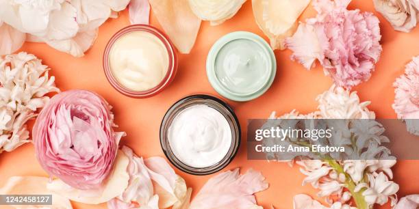 jars with creams amidst delicate flowers - makeup pile stock pictures, royalty-free photos & images