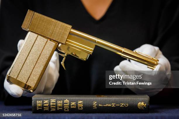 Limited edition replica of the gun from the film ‘The Man with the Golden Gun’ alongside a first edition book with rare binding of ‘The Man with the...
