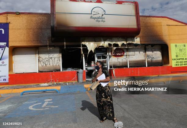 Woman stands in front of the building where unknown persons burnt down shops in Ciudad Juarez, state of Chihuahua, Mexico, on August 12, 2022 - The...