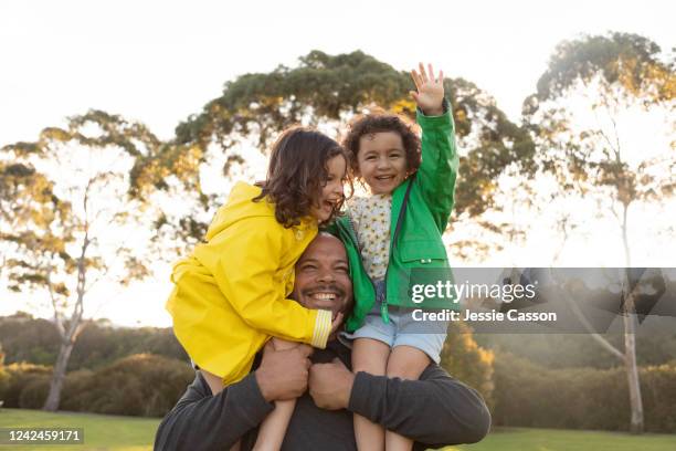 twin sisters have fun as father holds them on his shoulders - maori family stock-fotos und bilder