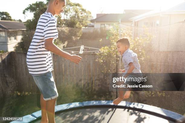 brothers having fun jumping on trampoline - auckland city people stock pictures, royalty-free photos & images