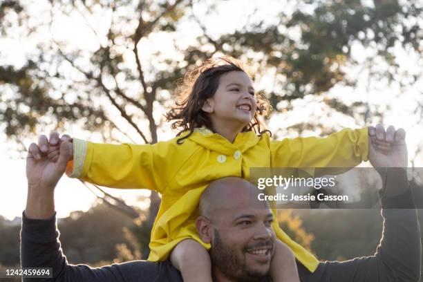 girl has fun as father carries her on his shoulders - new zealand yellow stock pictures, royalty-free photos & images