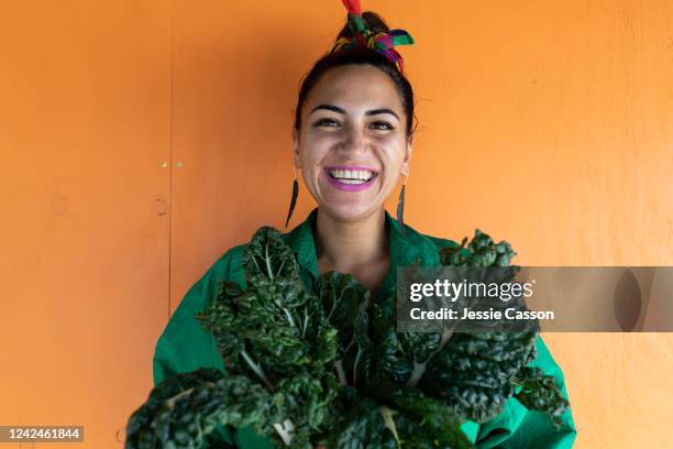 woman smiling holding silverbeet leaves looking at camera - frau und garten und gemüse stock-fotos und bilder