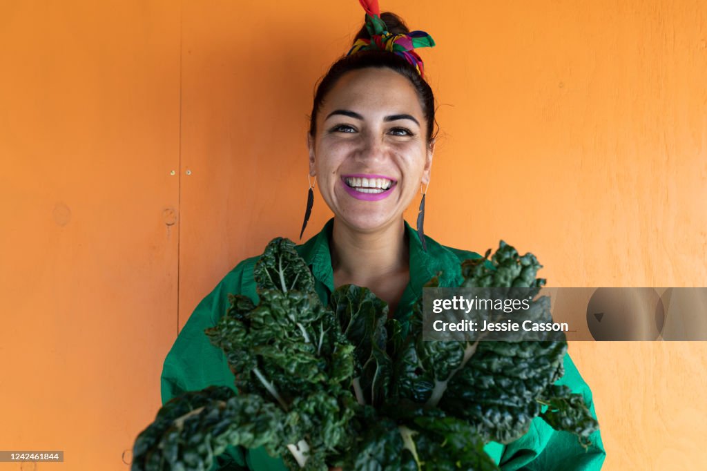 Woman smiling holding silverbeet leaves looking at camera