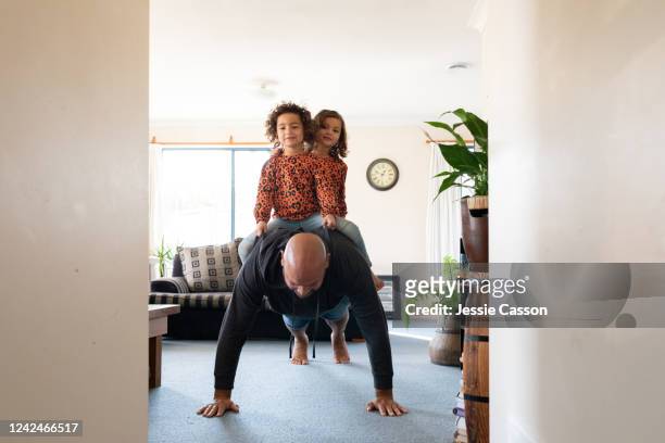 dad doing push-ups with twin daughters on his back - press ups stock pictures, royalty-free photos & images