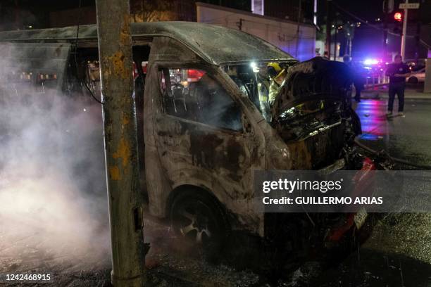 Firefighters work at the scene of a burnt collective transport vehicle after it was set on fire by unidentified individuals in Tijuana, Baja...