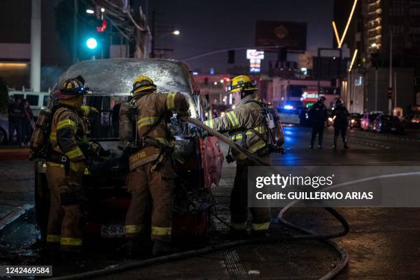 Firefighters work at the scene of a burnt collective transport vehicle after it was set on fire by unidentified individuals in Tijuana, Baja...