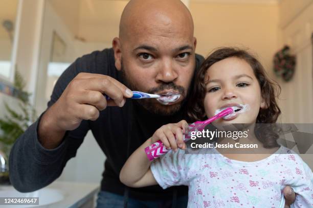 father and daughter brushing their teeth and looking into camera - brushing teeth ストックフォトと画像