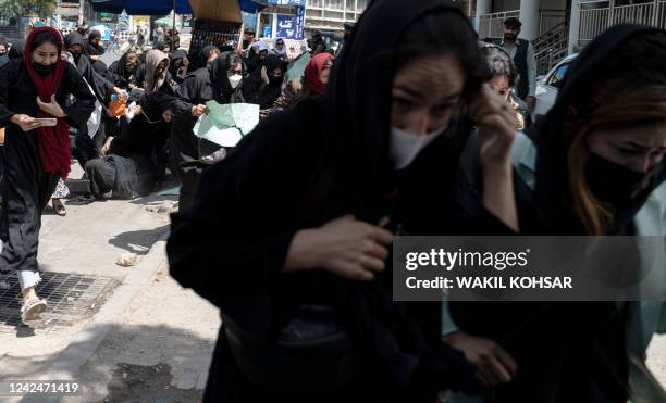 Taliban fighters fire into the air to disperse Afghan women protesters in Kabul on August 13, 2022. - Taliban fighters beat women protesters and...