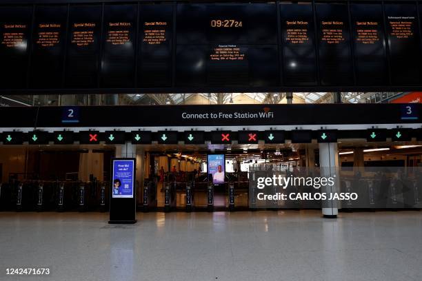 Photograph taken on August 13, 2022 shows closed trains ticket barriers and an announcement board warning that all trains from the station are...