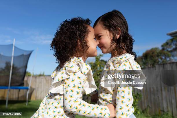 twin sisters giving each other a hongi - hongi stock-fotos und bilder