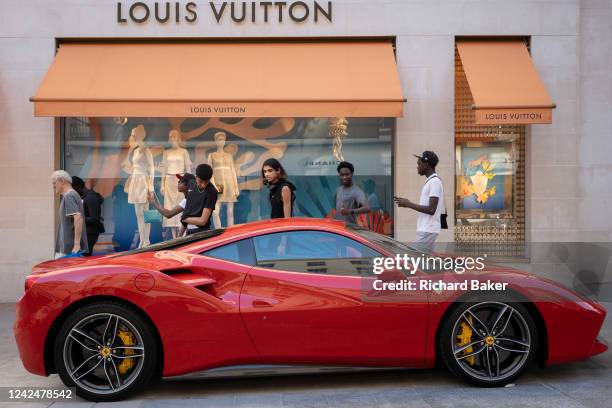 Group of young men admire a red Ferrari parked on the pavement outside the Louis Vuitton store in Bond Street, on 12th August 2022, in London,...