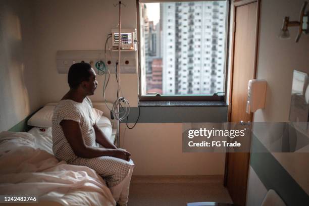senior patient looking through window at hospital - illness hospital stock pictures, royalty-free photos & images