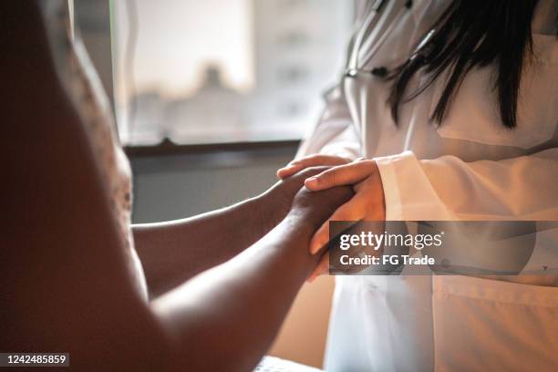mujer doctora cogiéndose de la mano de su paciente en la habitación del hospital - enfermedad crónica fotografías e imágenes de stock