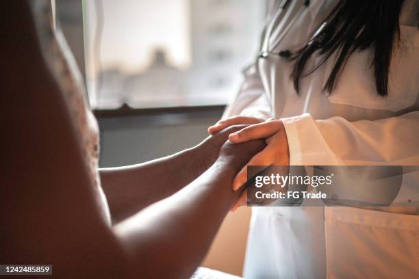 docteur féminin retenant des mains de son patient à la chambre d’hôpital - aide patient médecin photos et images de collection