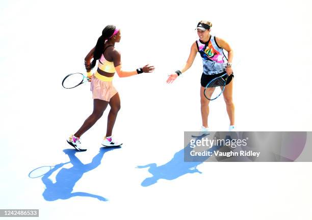 Coco Gauff of the United States high fives doubles partner Jessica Pegula of the United States while playing against Sania Mirza of India and Madison...