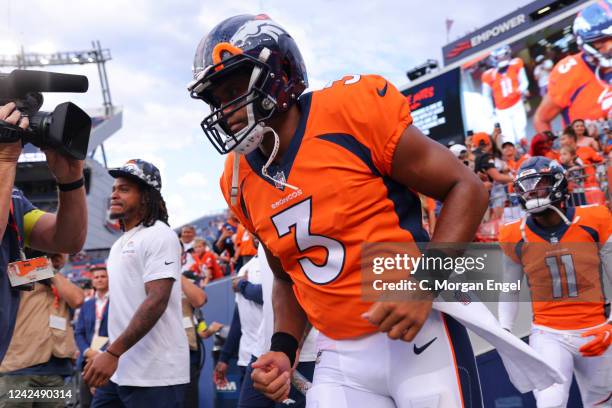 Russell Wilson of the Denver Broncos runs onto the field for warm-up before the game against the Dallas Cowboys at Empower Field At Mile High on...