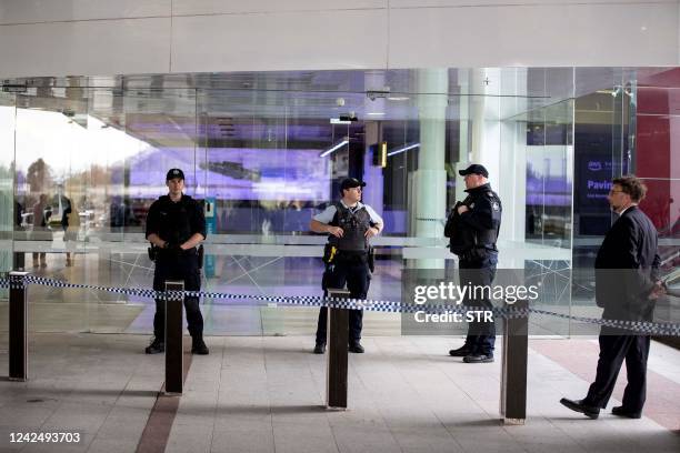 Police stand guard at the entrance of a terminal after a gunman opened fire at the airport in Canberra on August 14, 2022. - A gunman fired about...