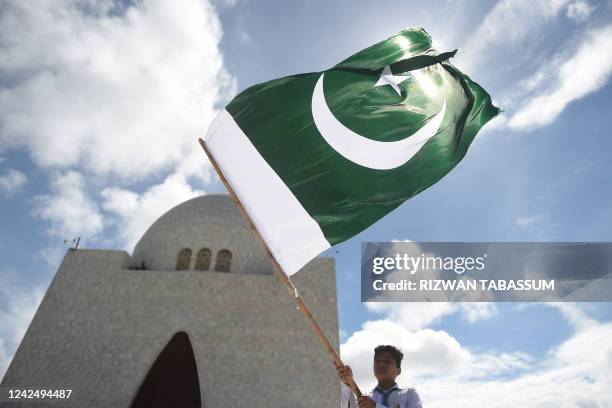 Student waves the national flag of Pakistan outside the mausoleum of country's founder Mohammad Ali Jinnah, after Pakistan's 75th Independence Day...