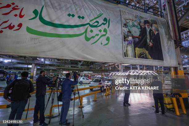 Journalists take images of Peugeot 207 and 206 car production lines at the Iran Khodro auto plant, west of the Iranian capital Tehran, on August 14...