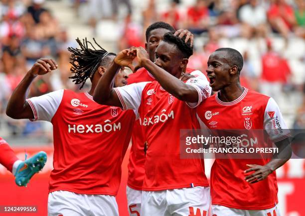 Reims' English forward Folarin Balogun celebrates with teammates after scoring a penalty kick during the French L1 football match between Stade de...