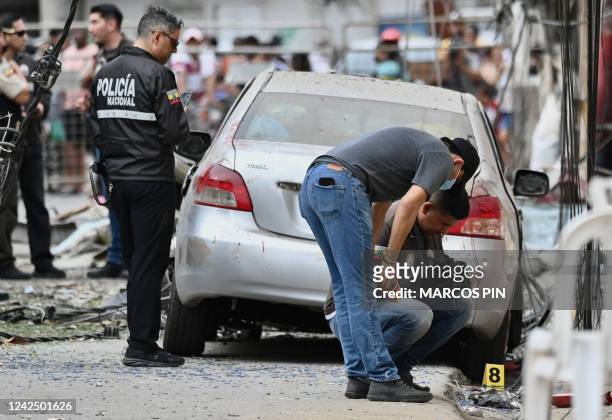 Members of the National Police inspect the site of an explosion, which the Ecuadorean government attributes to organized crime, in southern...