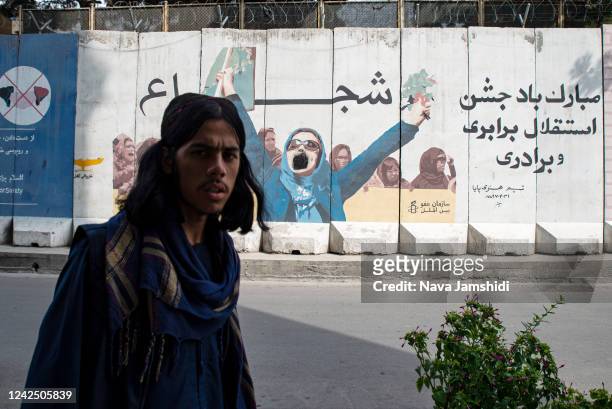 Man walks by a vandalized mural depicting a group of women on August 14, 2022 in Kabul, Afghanistan. The collapse of the economy and the freezing of...