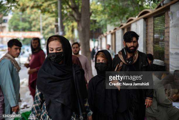 Women cover their faces when walking down a street on August 14, 2022 in Kabul, Afghanistan. The collapse of the economy and the freezing of Afghan...