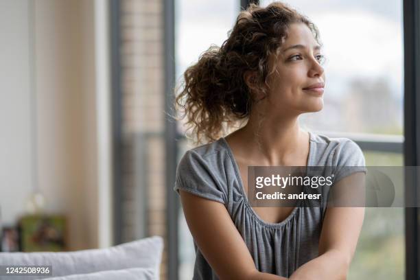 retrato de una mujer pensativa en casa durante la cuarentena - tranquilidad fotografías e imágenes de stock