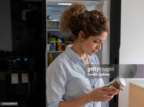 mujer en casa sacando ingredientes de la nevera - fechas de caducidad fotografías e imágenes de stock