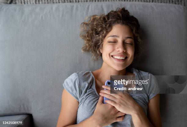 happy woman holding tight to her cell phone - dating stock pictures, royalty-free photos & images