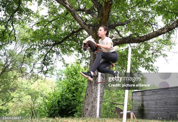 July 2022, Baden-Wuerttemberg, Stuttgart: Arwen jumps an obstacle course in a garden with her hobby horse. She practices the sport of hobby horsing....