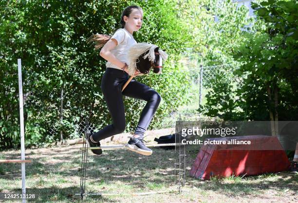 July 2022, Baden-Wuerttemberg, Stuttgart: Arwen jumps an obstacle course in a garden with her hobby horse. She practices the sport of hobby horsing....
