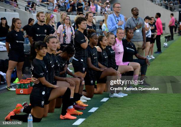 Substitute soccer players of Angel City FC take a knee during the national anthem before the start of the game against Chicago Red Stars during...