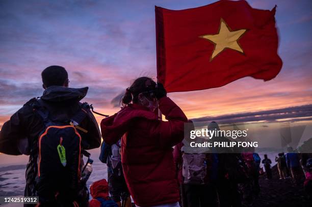Tourist holds a Vietnamese flag as people watching the sunrise from the summit of Mount Fuji early on August 15 some 70 kilometres west of the...