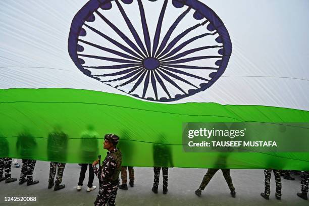 Indian paramilitary troopers hold a giant Indian national flag during the celebrations to mark India's 75th Independence Day at Lal Chowk in Srinagar...