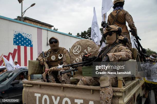 Taliban soldiers ride down the street in a pickup truck during a celebration of the first anniversary of the Taliban's return to power on August 15,...