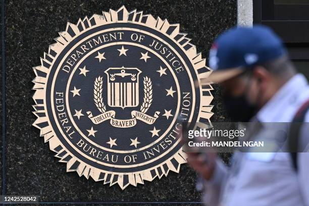 Pedestrian walks past a seal reading "Department of Justice Federal Bureau of Investigation", displayed on the J. Edgar Hoover FBI building, in...