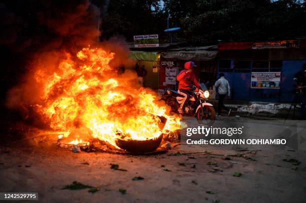 Supporter of Kenya's Azimio La Umoja Party presidential candidate Raila Odinga on a motorbike passes by burning tyres during a protest against the...