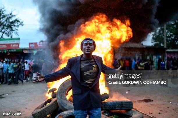 Supporter of Kenya's Azimio La Umoja Party presidential candidate Raila Odinga gestures past a fire during a protest against the results of Kenya's...