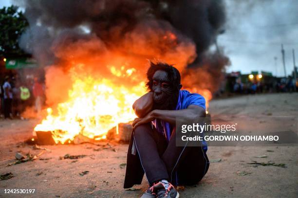 Supporter of Kenya's Azimio La Umoja Party presidential candidate Raila Odinga reacts past burning tyres during a protest against the results of...